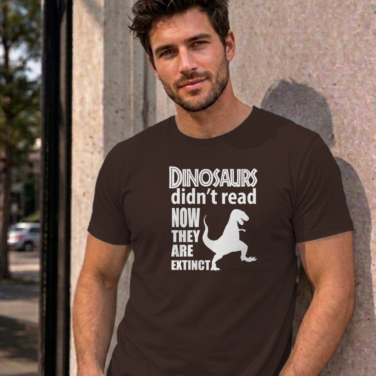 Man wearing the dark chocolate Dinosaurs Didn't Read graphic tee