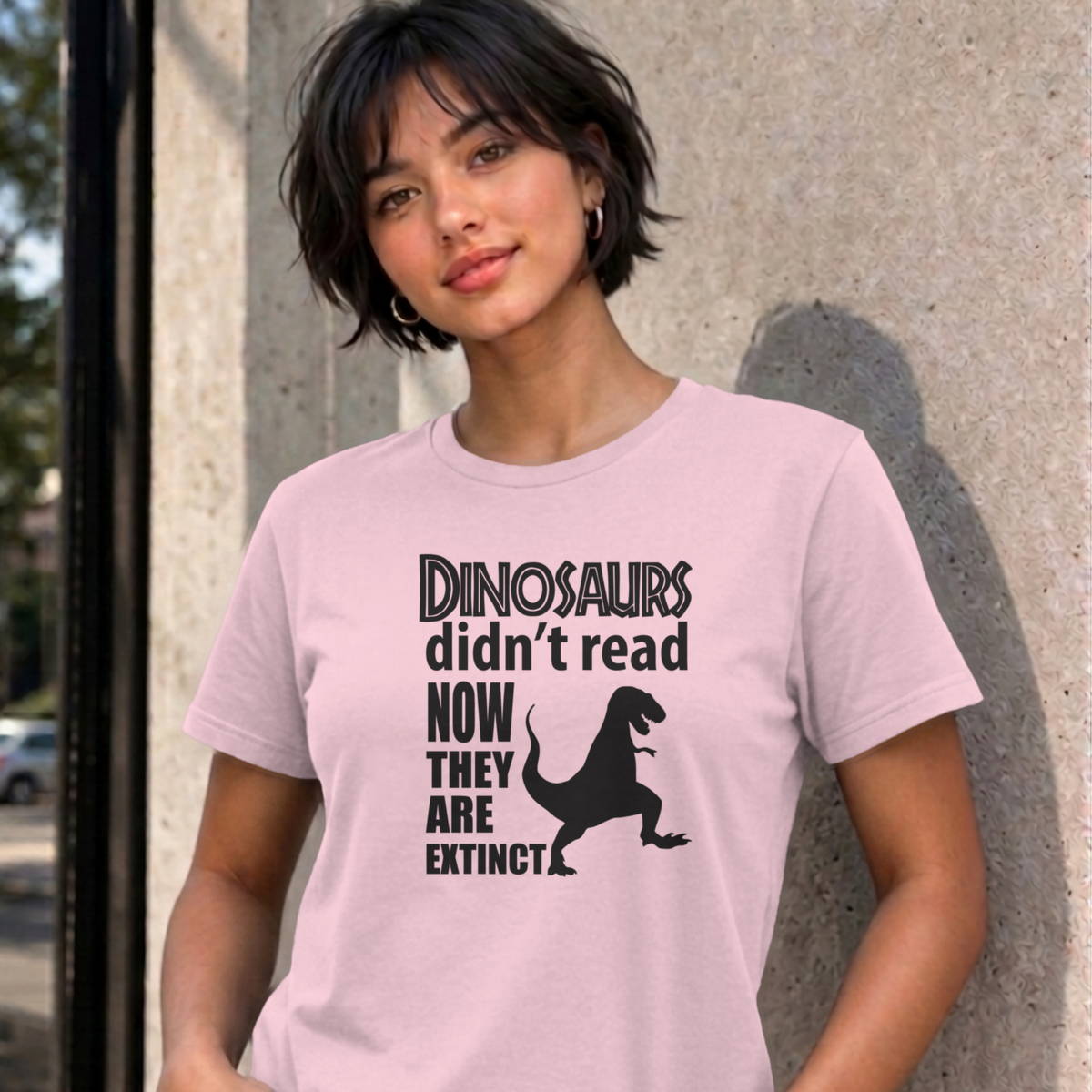 Woman wearing the light pink Dinosaurs Didn't Read graphic tee