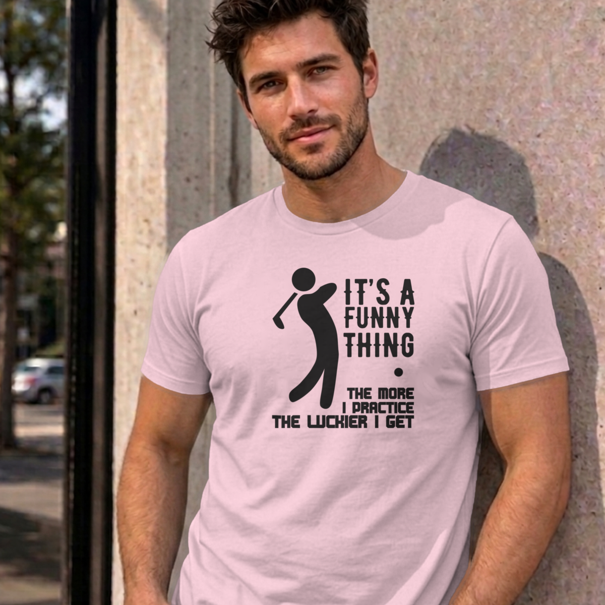 Man wearing the light pink The More I Practice graphic tee