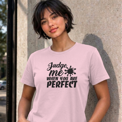 Woman wearing the light pink Judge Me When You Are Perfect graphic tee