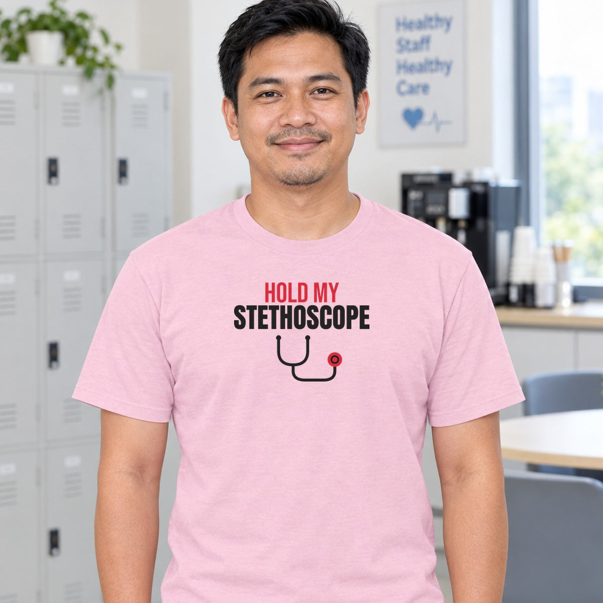 Man wearing the light pink Hold My Stethoscope graphic tee