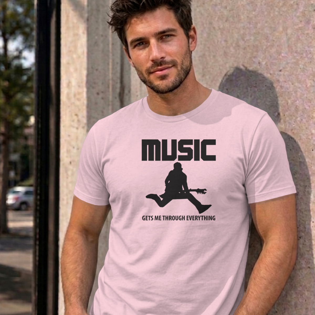 Man wearing the light pink Music Gets Me Through graphic tee