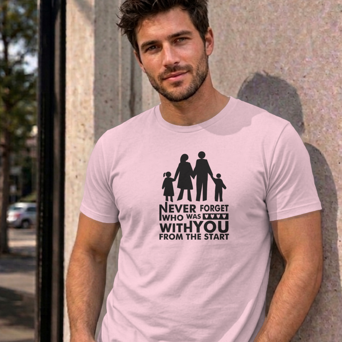 Man wearing the light pink Never Forget Family graphic tee