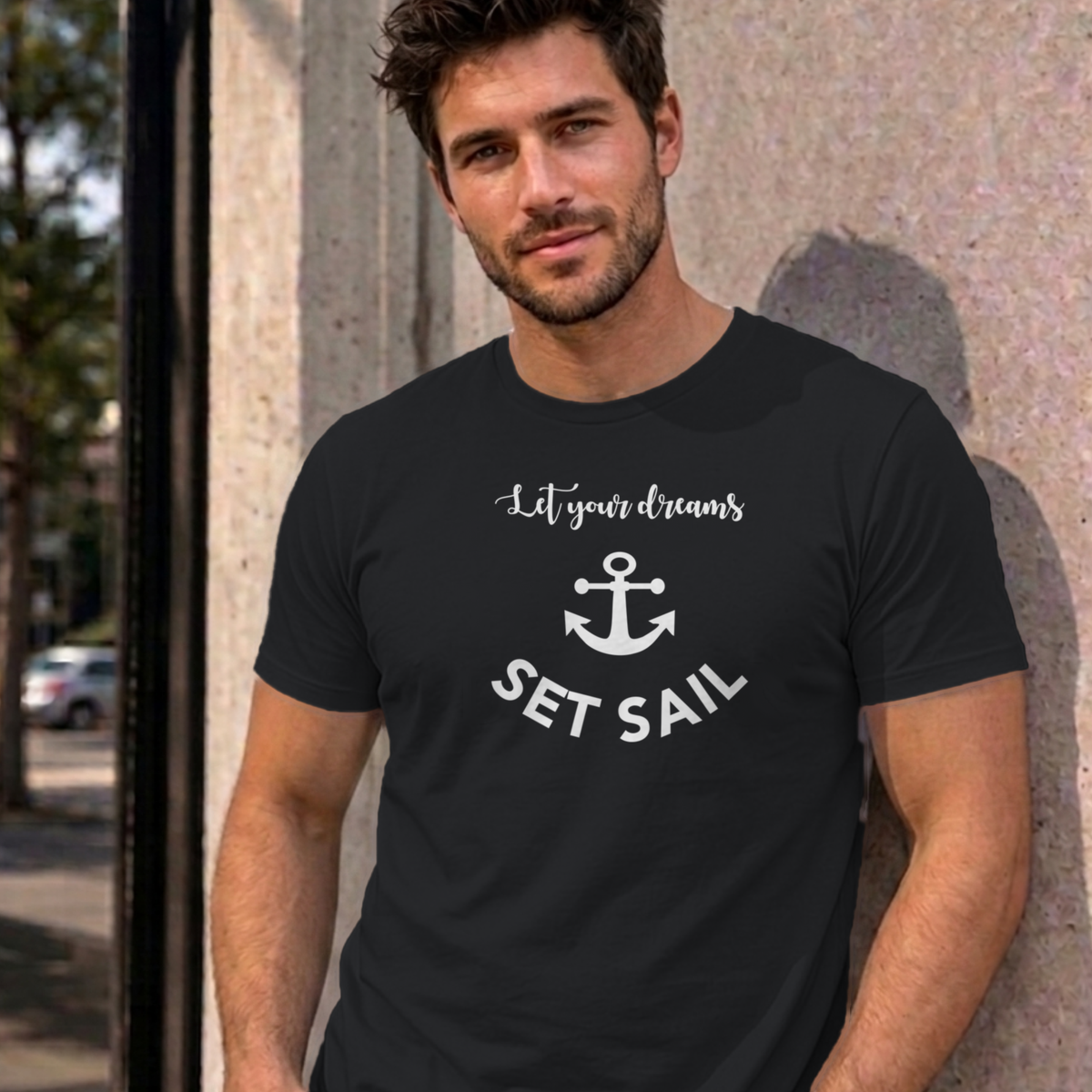 Man wearing the black Let Your Dreams Set Sail graphic tee