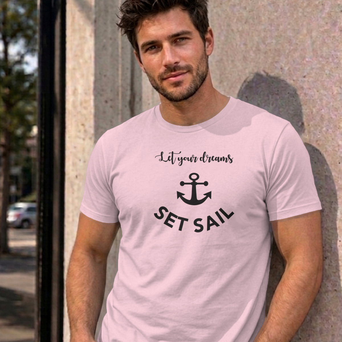 Man wearing the light pink Let Your Dreams Set Sail graphic tee