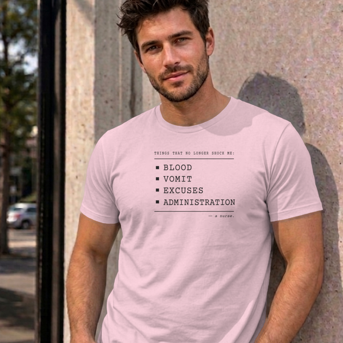 Man wearing the light pink Nurse No Longer Shocked graphic tee