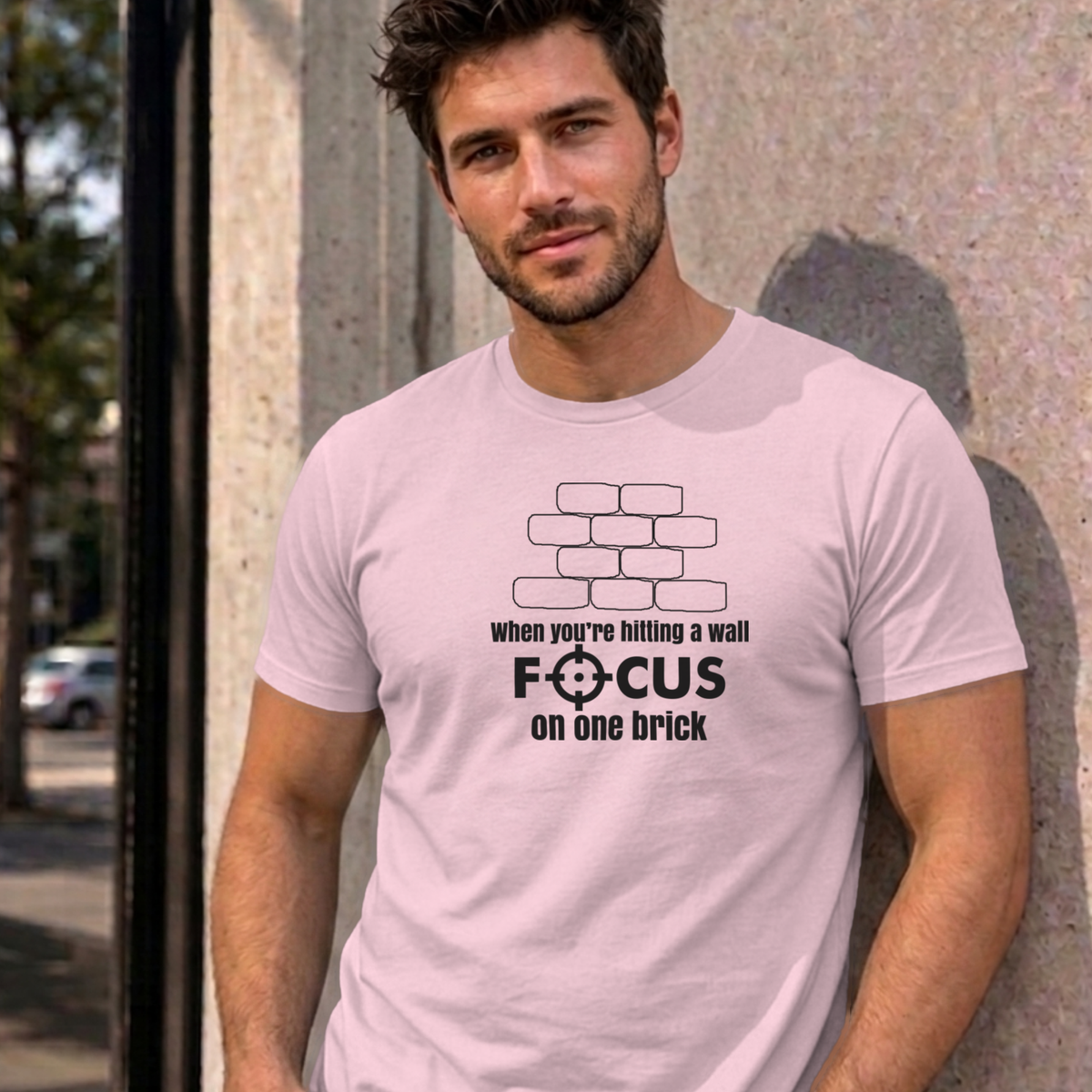 Man wearing the light pink Focus on One Brick graphic tee