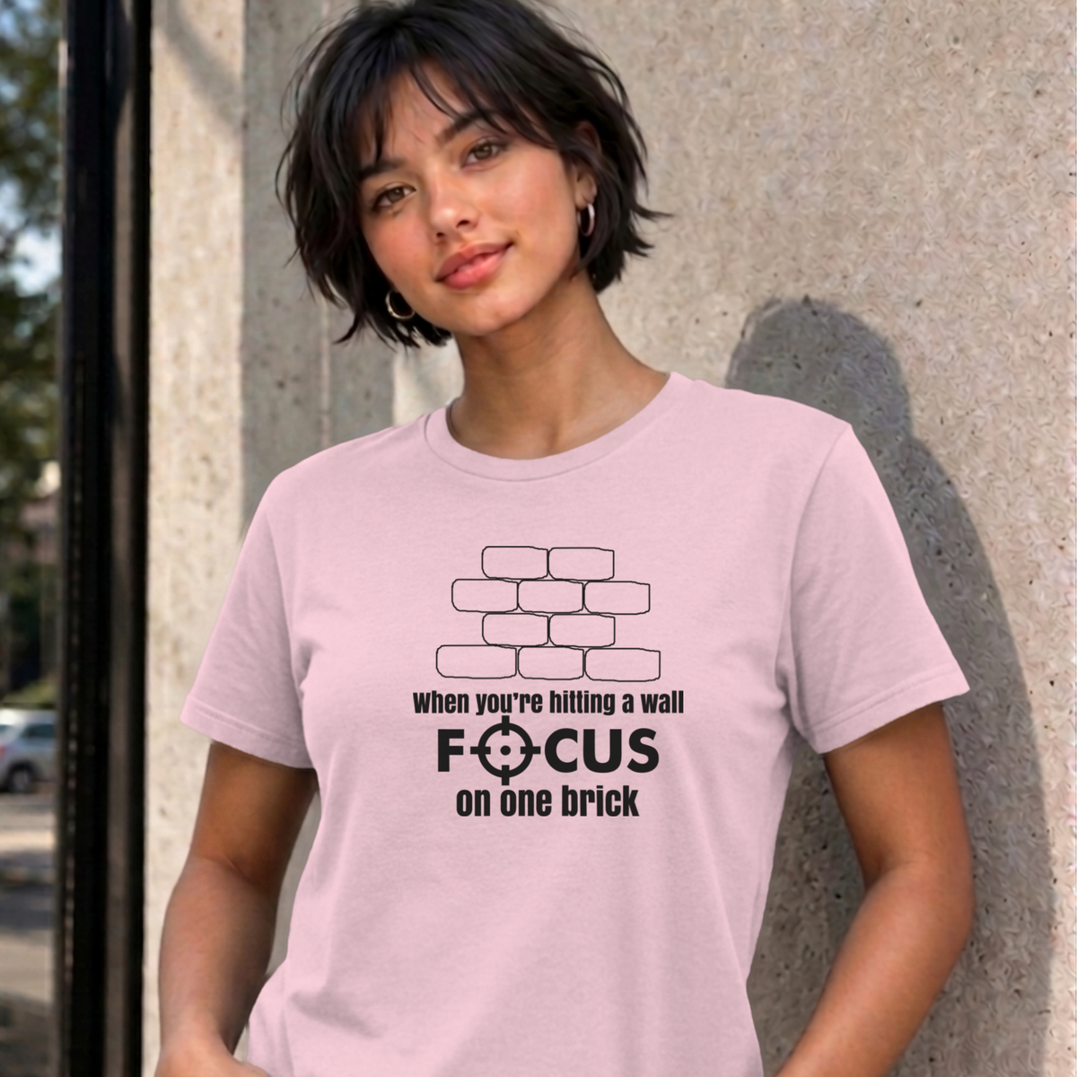 Woman wearing the light pink Focus on One Brick graphic tee