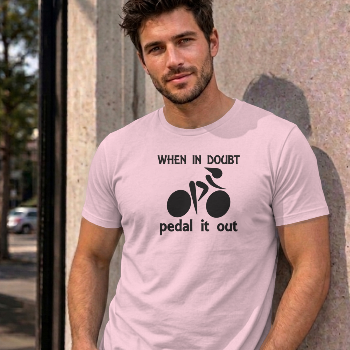 Man wearing the light pink Pedal It Out graphic tee